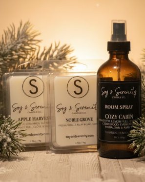 Small Christmas stocking stuffer gifts featuring soy wax melts and a room spray styled with greenery in warm light